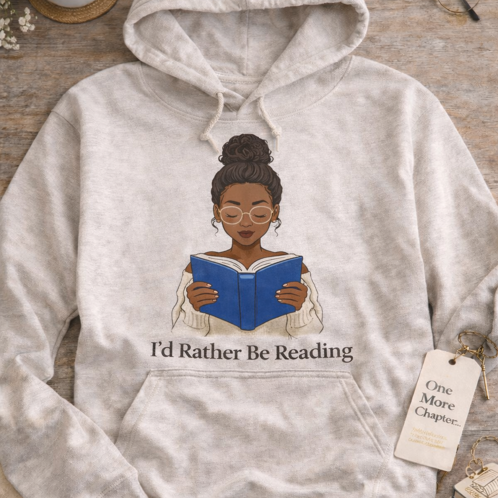Gray hoodie with a graphic of a woman reading a book and 'I'd Rather Be Reading' text, placed on a wooden surface with a cup of coffee and books.